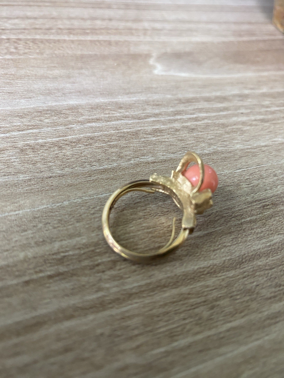 Avon vintage gold toned ring showcasing a single faux coral-colored bead.