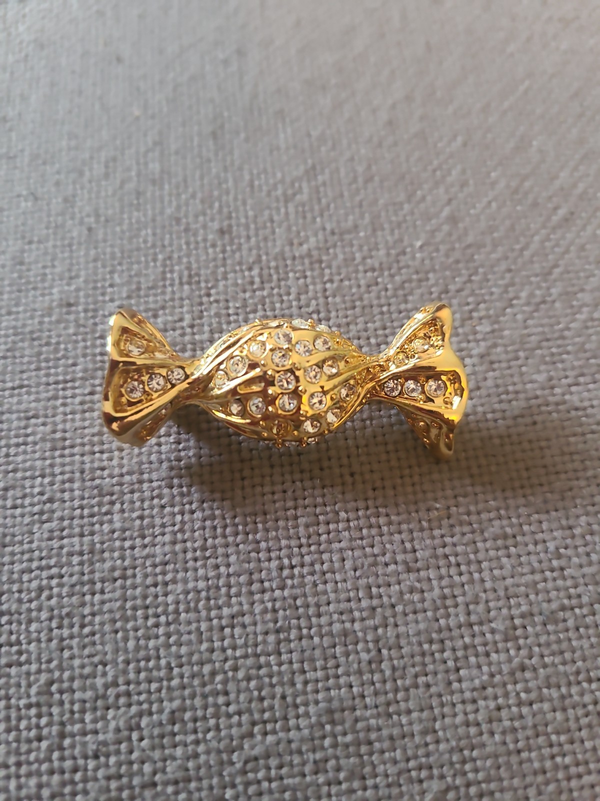 Brooch in goldtone wrapped candy with clear rhinestones. Vintage