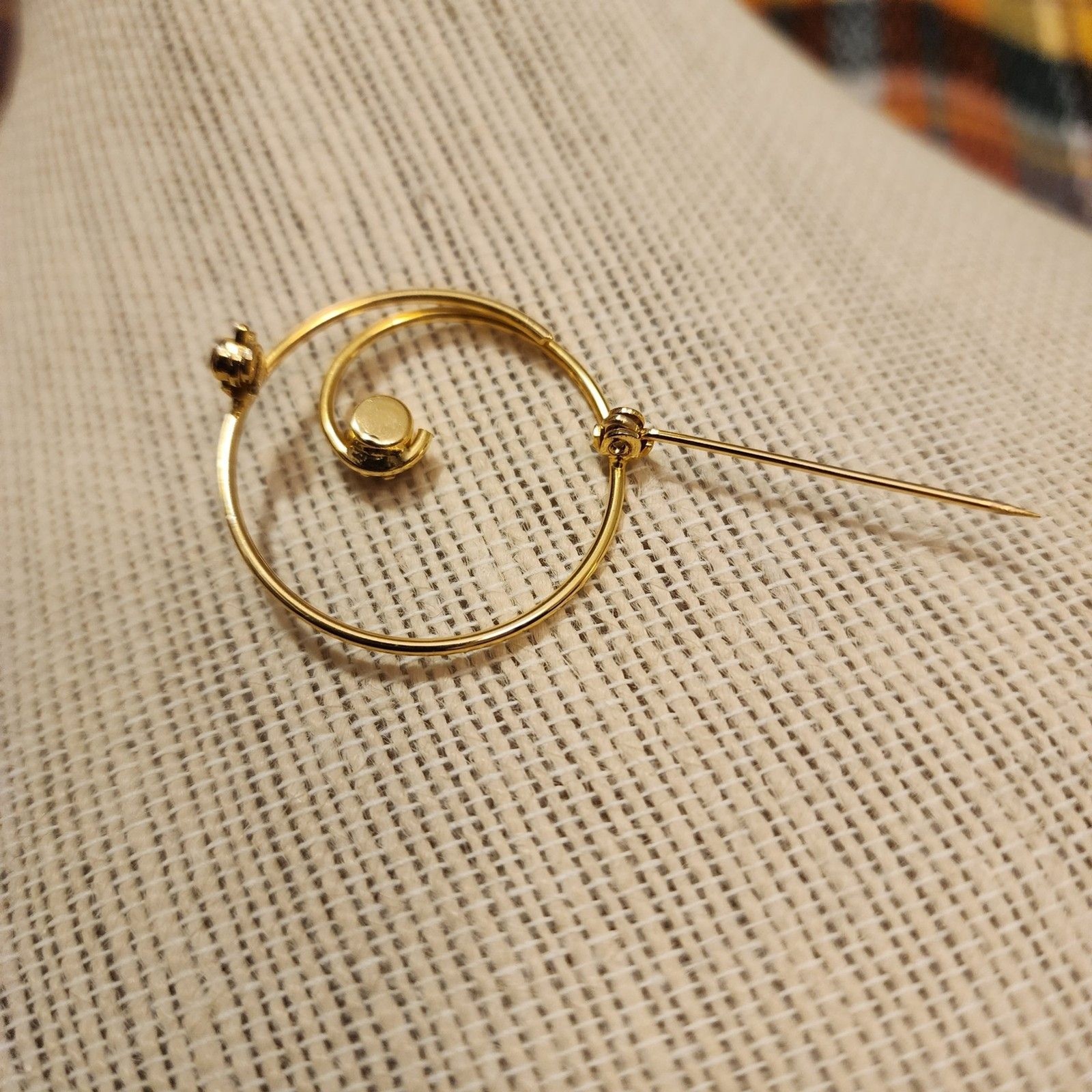 Gold Tone Swirl Circle Brooch With Red Rhinestone Accent.